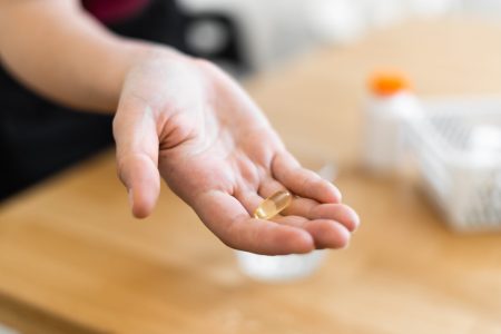 Woman's hands with supplements pills and glass of water. Self health care with preventive medicine. High quality photo